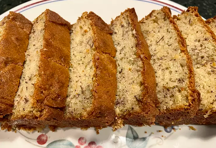 A loaf of freshly baked banana bread on a wooden cutting board.