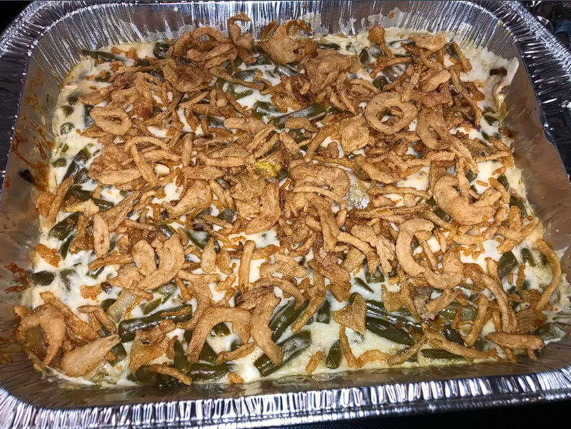 A freshly baked green bean casserole being served at a holiday dinner table.