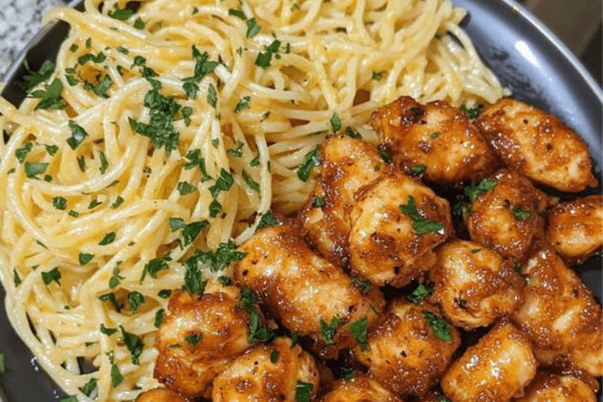 Garlic butter chicken bites served alongside lemon Parmesan spaghetti, creating a zesty and creamy meal.