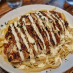 Garlic butter chicken served with creamy ricotta Alfredo pasta, topped with fresh herbs for a rich and flavorful meal.