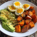 Avocado, egg, and roasted sweet potato bowl topped with fresh ingredients