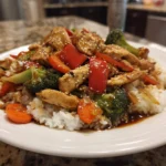 A colorful bowl of savory chicken stir-fry with vibrant vegetables and sauce.