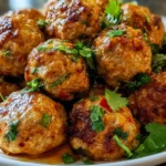 Delicious Thai baked chicken meatballs garnished with herbs on a platter.