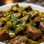 A steaming bowl of Mexican beef green chili garnished with fresh herbs.