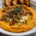 Delicious Pumpkin Whipped Feta Dip in a serving bowl garnished with herbs.