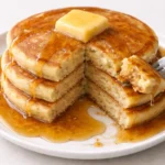 Delicious fluffy pancakes stacked with syrup and berries
