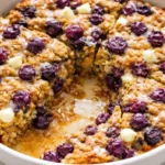 Healthy blueberry oatmeal baked breakfast dish topped with fresh blueberries