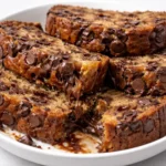 A slice of super moist chocolate chip banana bread on a wooden board