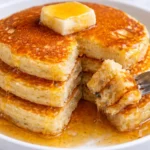 Stack of fluffy pancakes drizzled with maple syrup and topped with berries
