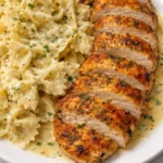 Plate of Baked Herb Chicken with creamy Alfredo bowtie pasta garnished with herbs