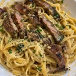 Creamy garlic parmesan pasta served with tender steak on a plate.
