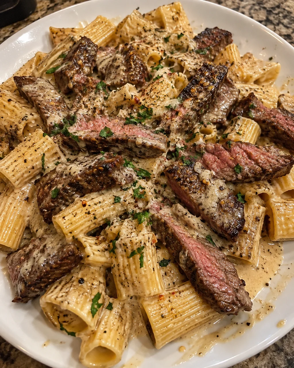 Creamy Garlic Parmesan Steak with Rigatoni Pasta, garnished and plated appetizingly.