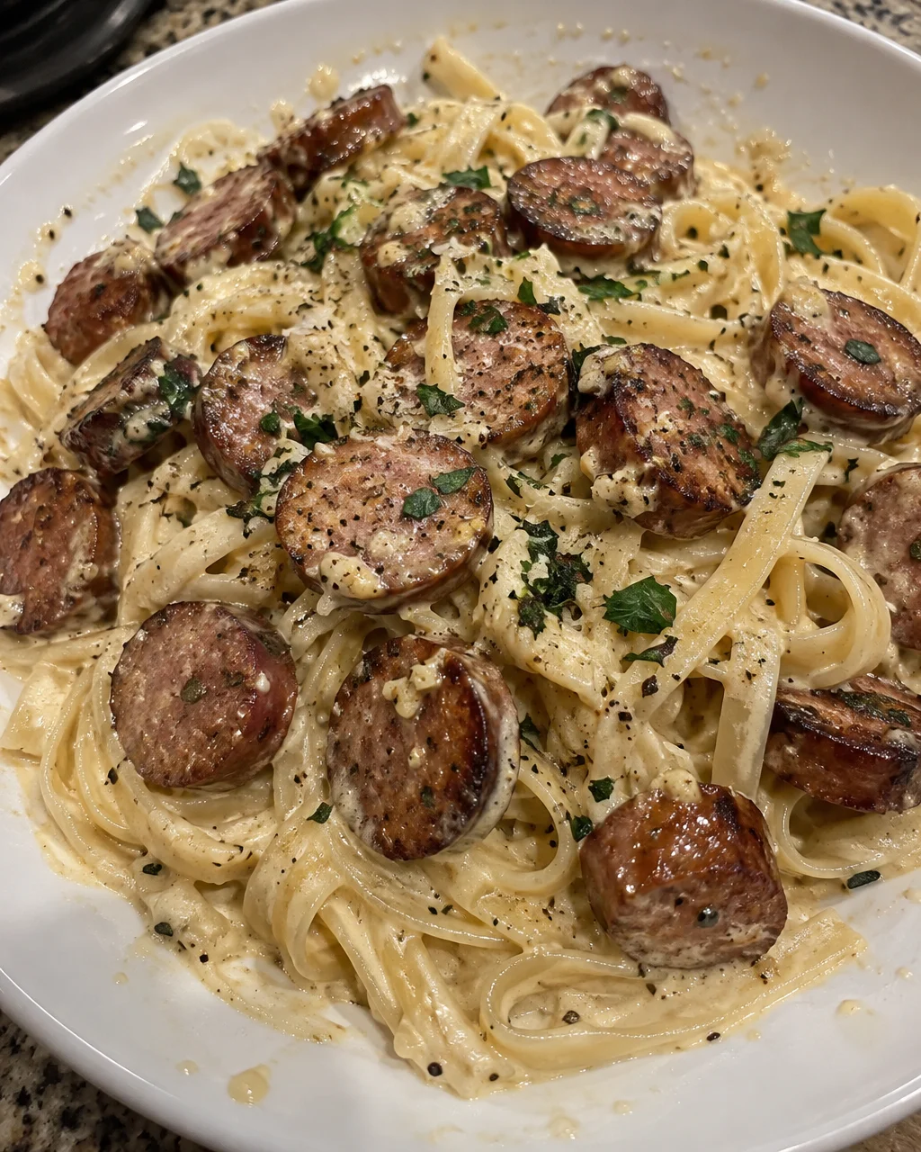 Creamy Parmesan pasta with garlic butter sausage bites served in a bowl.